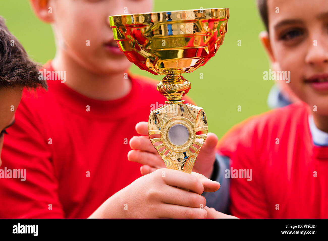Kids soccer football - young children players celebrating with a trophy after match on soccer field Stock Photo