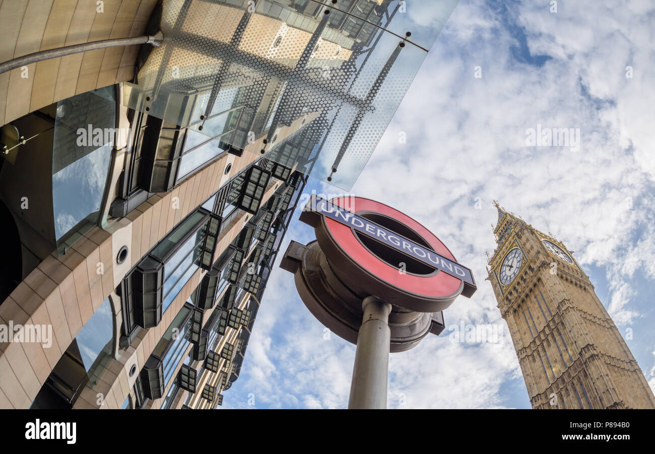 Looking up at Westminster station and underground sign and Big Ben in London against a blue sky with clouds taken with a wide angle lens Stock Photo