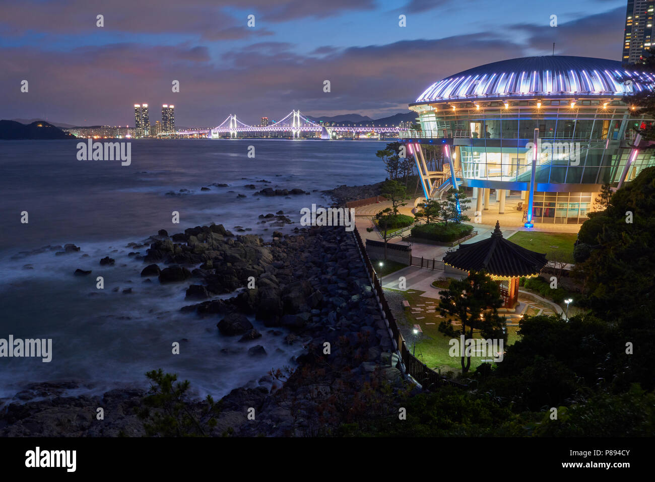 Seascape in Busan, South Korea, with APEC building in the foreground and city lights  in the far horizon. Stock Photo