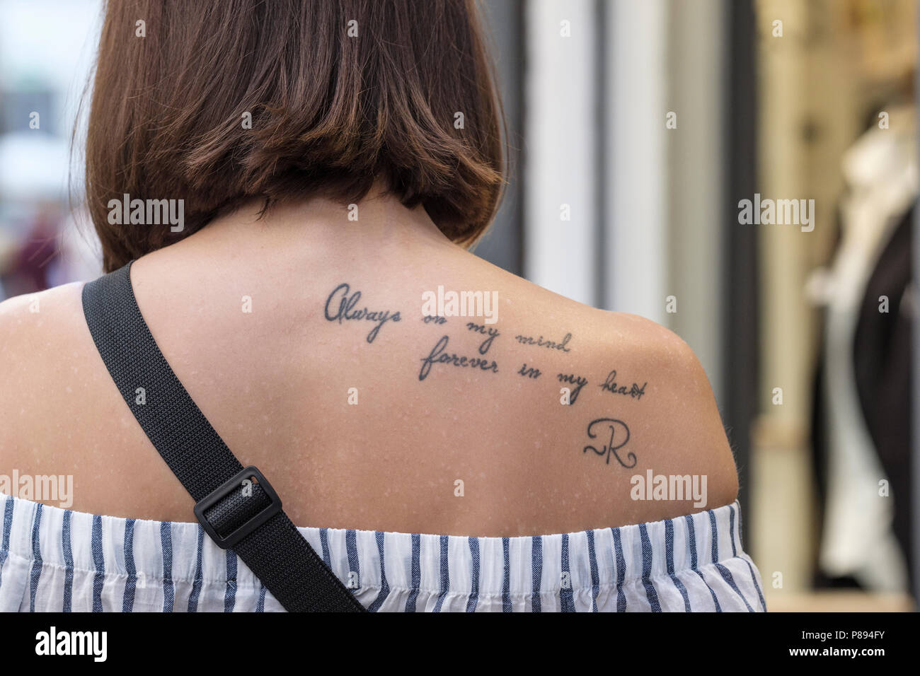 Tattoo of the words, always on my mind, forever in my heart, on young ladies rear shoulder, Lucca, Tuscany, Italy, Europe, Stock Photo