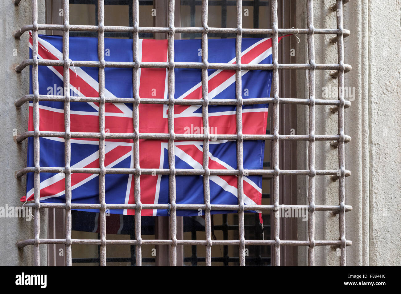 British flag behind window security bars, old city street in Lucca, Tuscany, Italy, Europe, Stock Photo