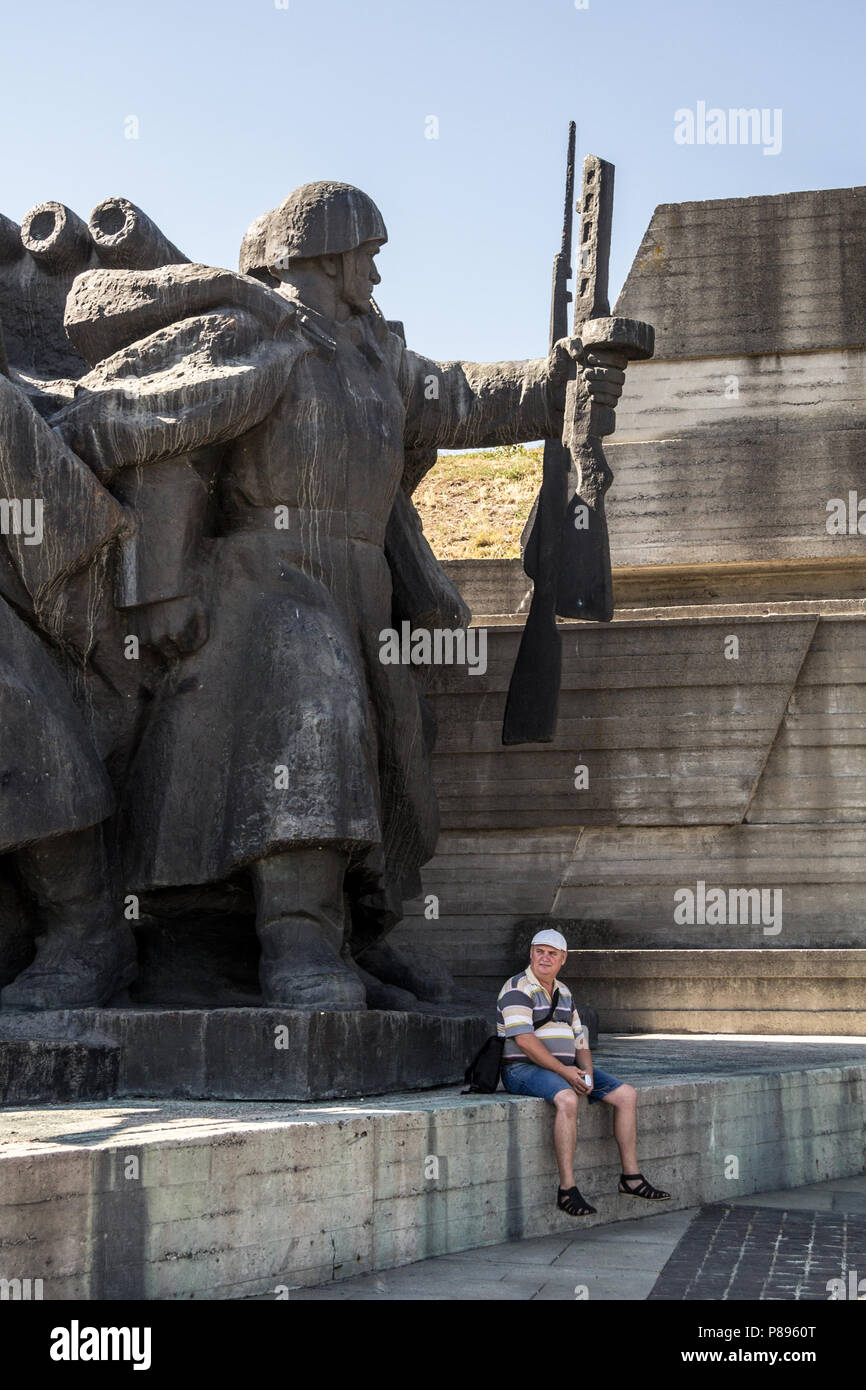 KIEV, UKRAINE - AUGUST 9, 2015: Man sitting under a gigantic Communist statue in the museum of the Great Patriotic war, dedicated to the history of Uk Stock Photo