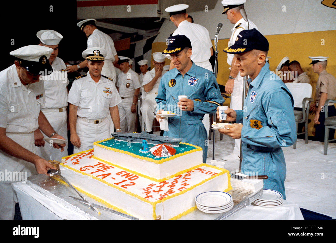 Gemini-12 astronaut James A. Lovell Jr. (left),  and Edwin E. Aldrin Jr. (right), pilot, eat a piece of cake presented the two astronauts by crew members of the prime recovery ship, USS Wasp Stock Photo