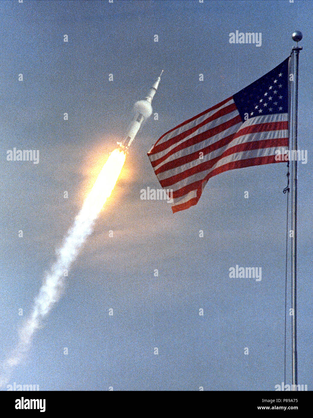 The American flag heralds the flight of Apollo 11, the first Lunar landing mission. The Apollo 11 Saturn V space vehicle lifted off with astronauts Neil A. Armstrong, Michael Collins and Edwin E. Aldrin, Jr., at 9:32 a.m. EDT July 16, 1969, from Kennedy Space Center's Launch Complex 39A. Stock Photo