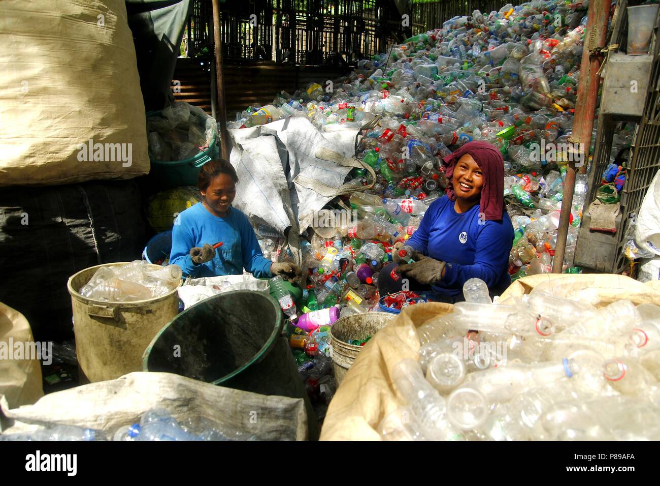 ANGONO, RIZAL, PHILIPPINES - JULY 4 2018: Workers of a materials recovery facility sort through plastic waste and segregate them for proper recycling. Stock Photo