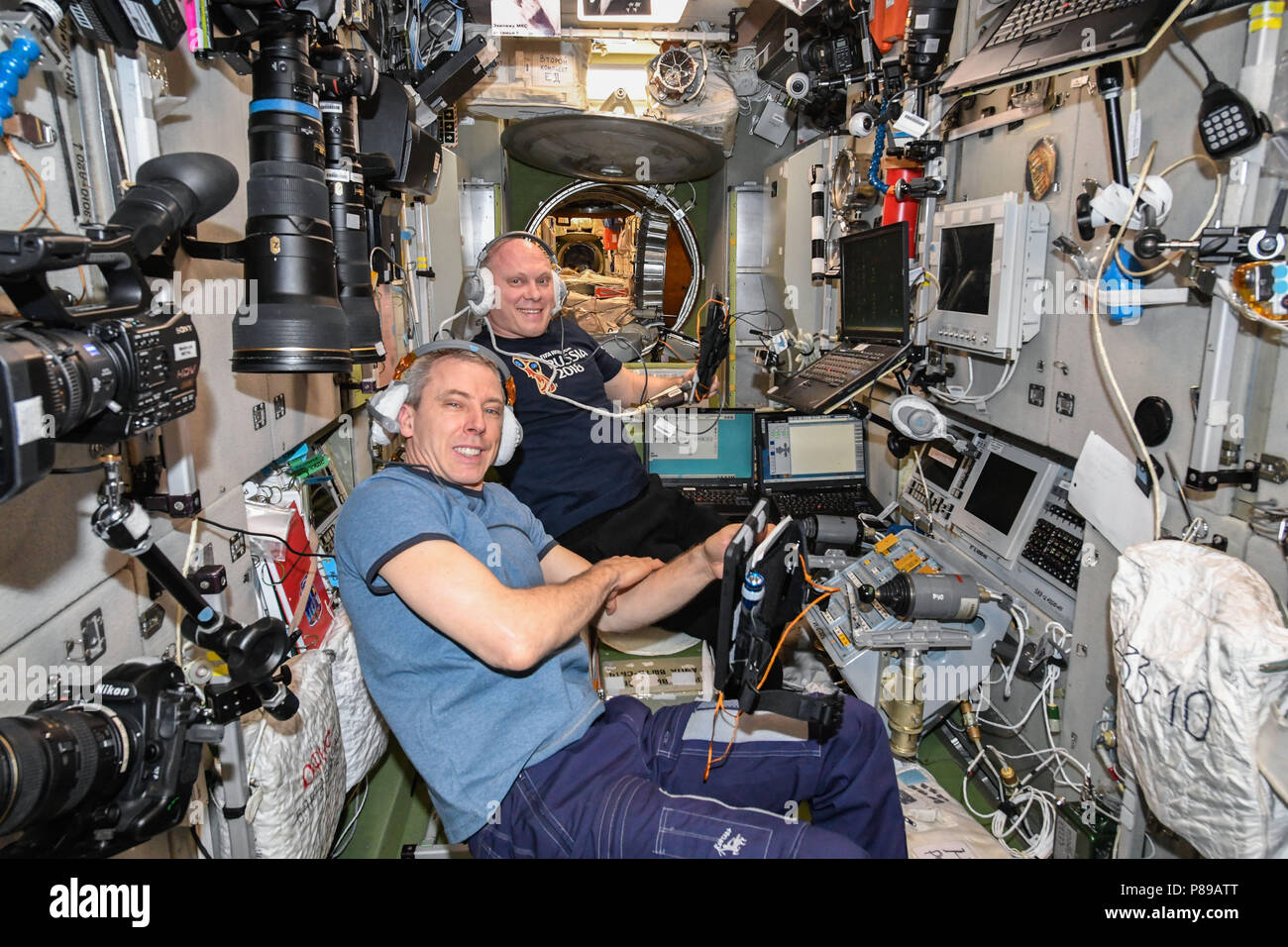 NASA astronaut Drew Feustel, foreground, and Russian cosmonaut Oleg Artemyev practice evacuation procedures inside the Zvzeda service module of the International Space Station in the unlikely event an emergency would require the crew to enter their Soyuz spacecraft and return to Earth June 20, 2018 in Earth Orbit. Stock Photo