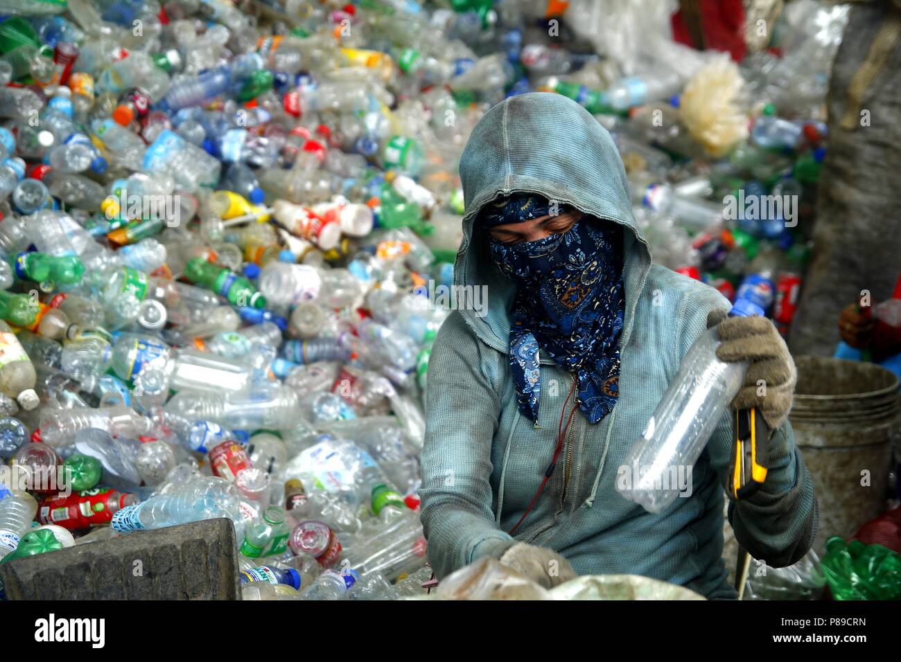 ANGONO, RIZAL, PHILIPPINES - JULY 4 2018: Workers of a materials recovery facility prepare plastic bottles for proper recycling. Stock Photo