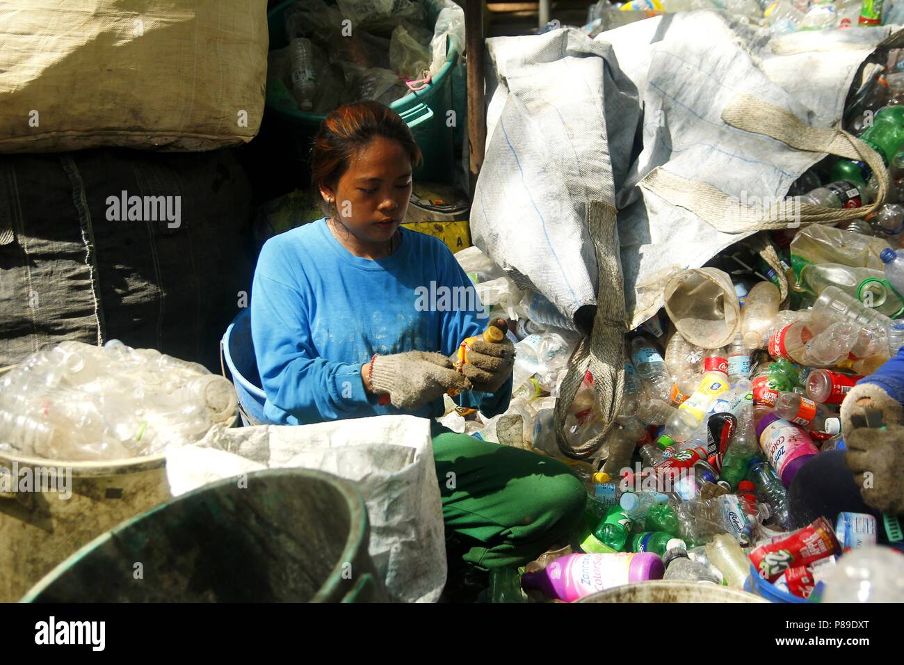 ANGONO, RIZAL, PHILIPPINES - JULY 4 2018: Workers of a materials recovery facility prepare plastic bottles for proper recycling. Stock Photo
