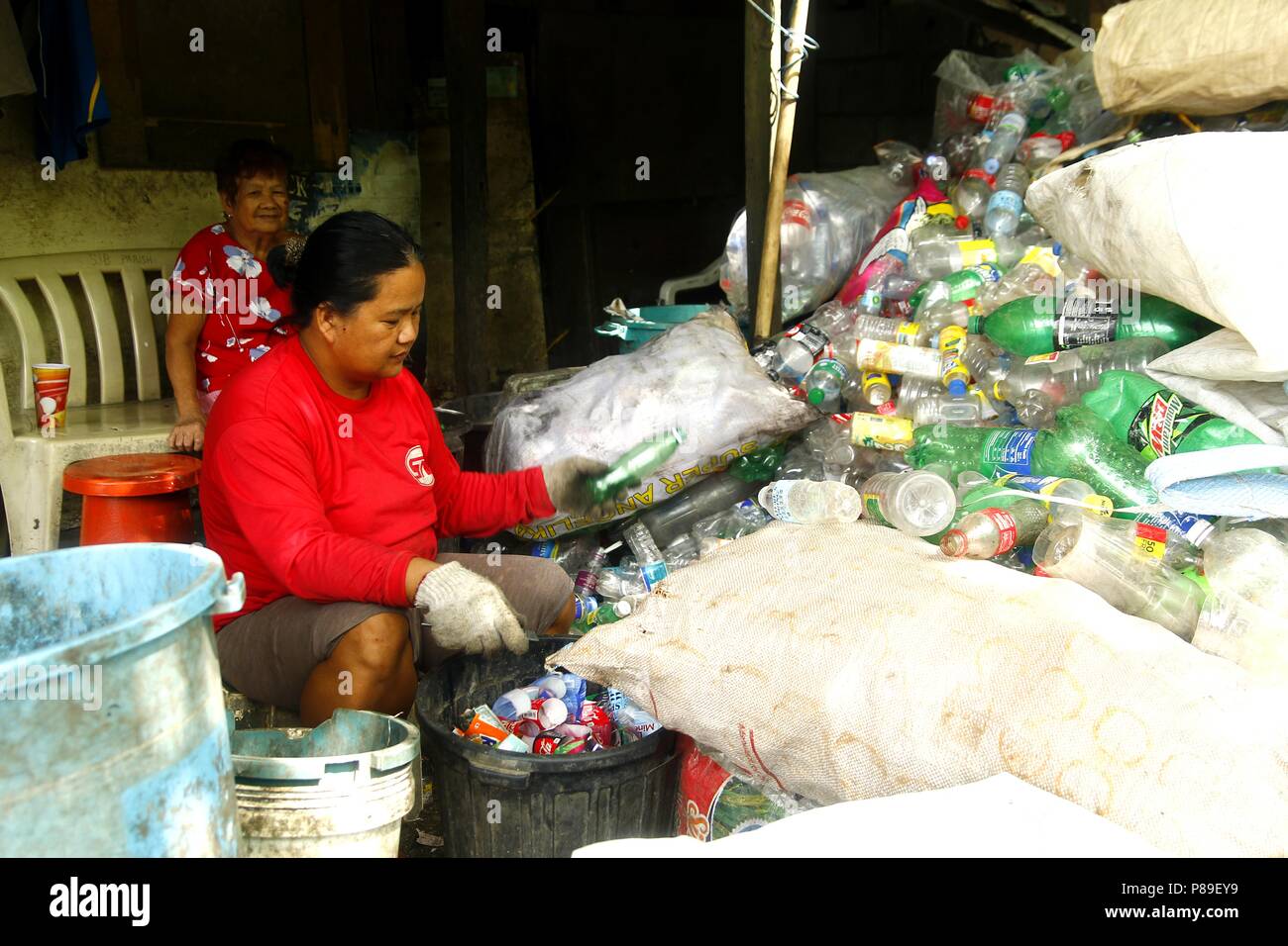 ANGONO, RIZAL, PHILIPPINES - JULY 4 2018: Workers of a materials recovery facility sort through plastic waste and segregate them for proper recycling. Stock Photo