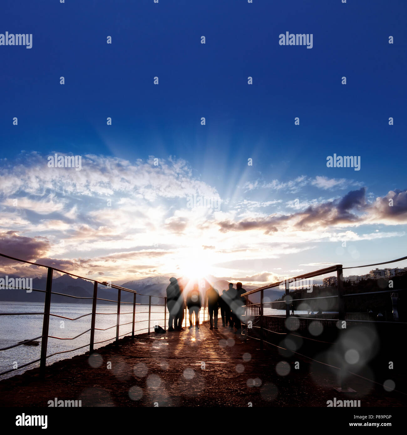 silhouetted people walking on street over sunset sky with sunbeam Stock ...