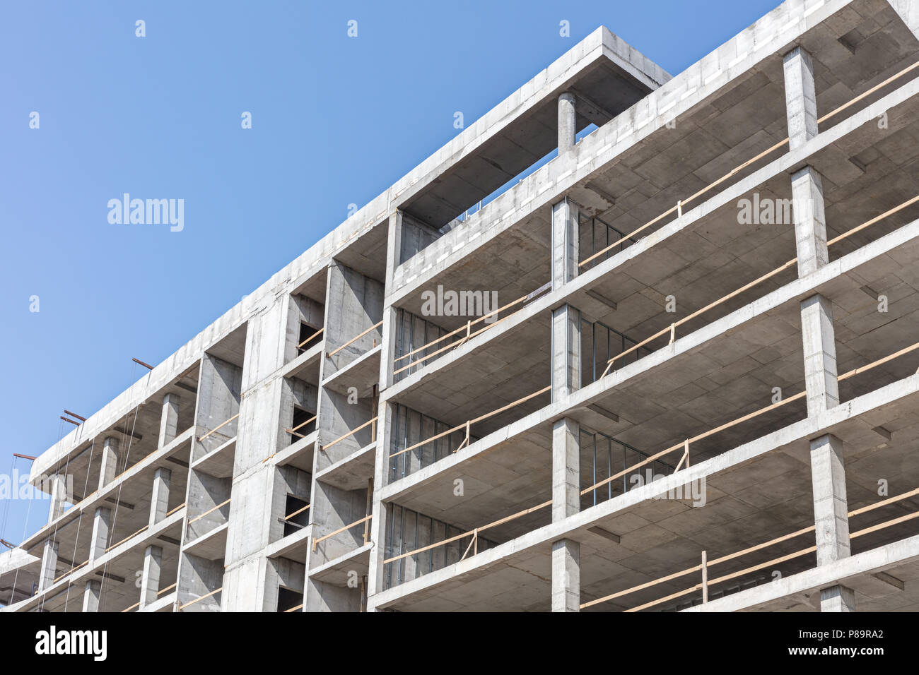high-rise concrete building under construction against blue clean sky background Stock Photo