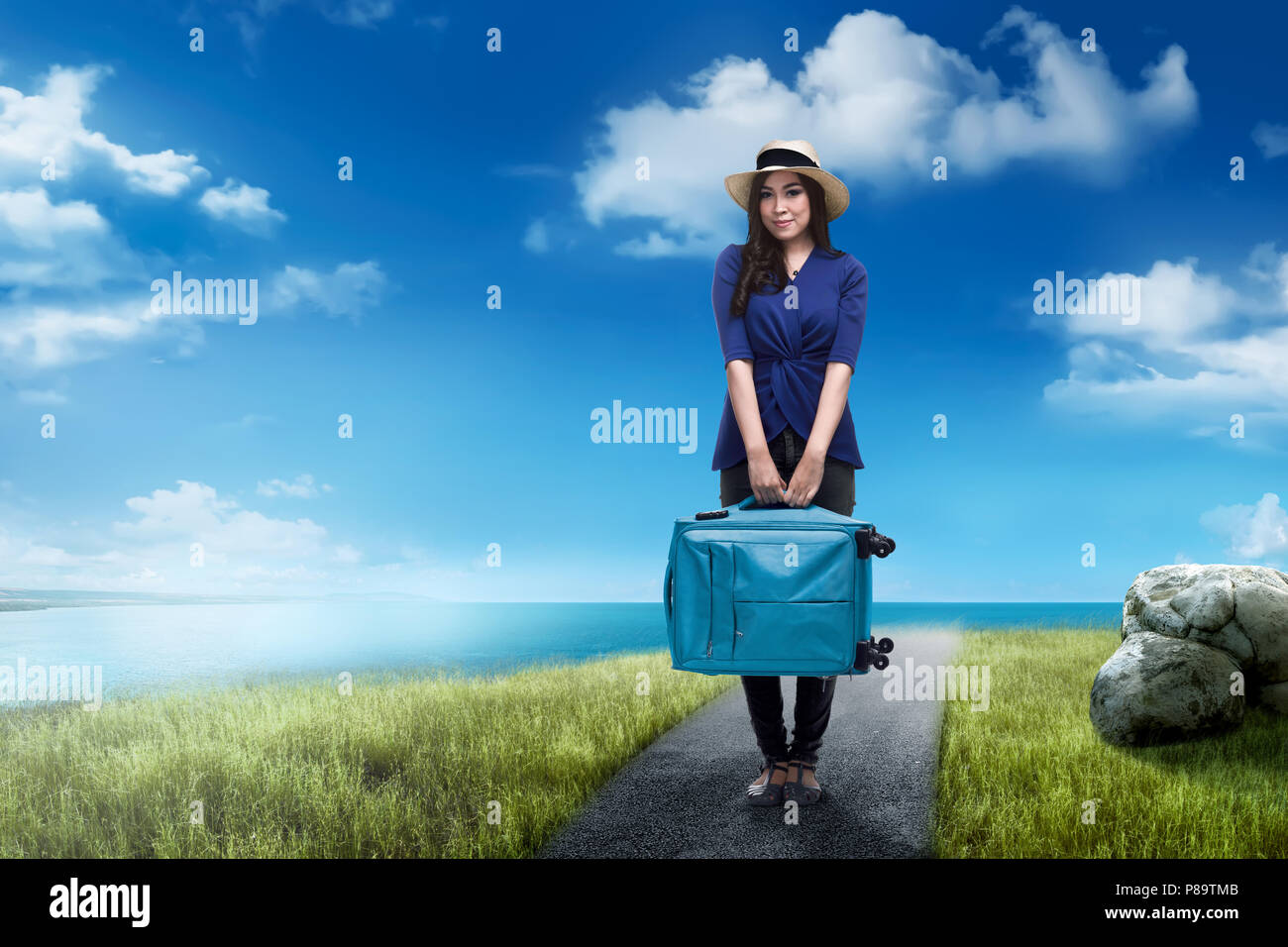 Young asian traveler woman carrying suitcase with blue sky background Stock Photo