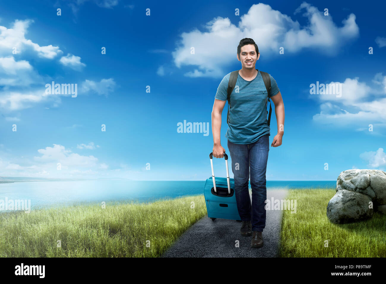 Handsome asian traveler man with backpack walking against ocean background Stock Photo