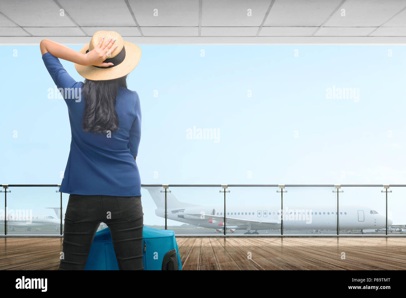 Rear view asian traveler woman with suitcase waiting the plane on airport Stock Photo