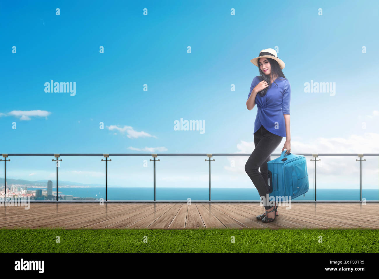 Happy asian traveler woman with suitcase standing at hotel balcony Stock Photo
