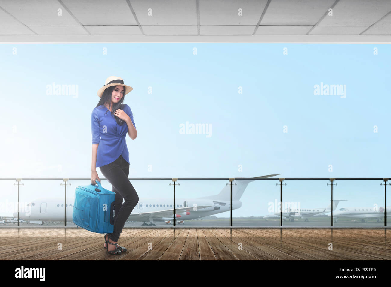 Smiling asian female traveler carrying suitcase on the airport Stock Photo