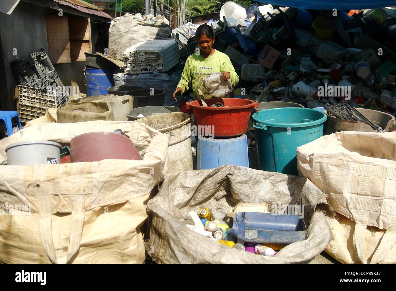 ANGONO, RIZAL, PHILIPPINES - JULY 4 2018: Workers of a materials recovery facility sort through plastic waste and segregate them for proper recycling. Stock Photo