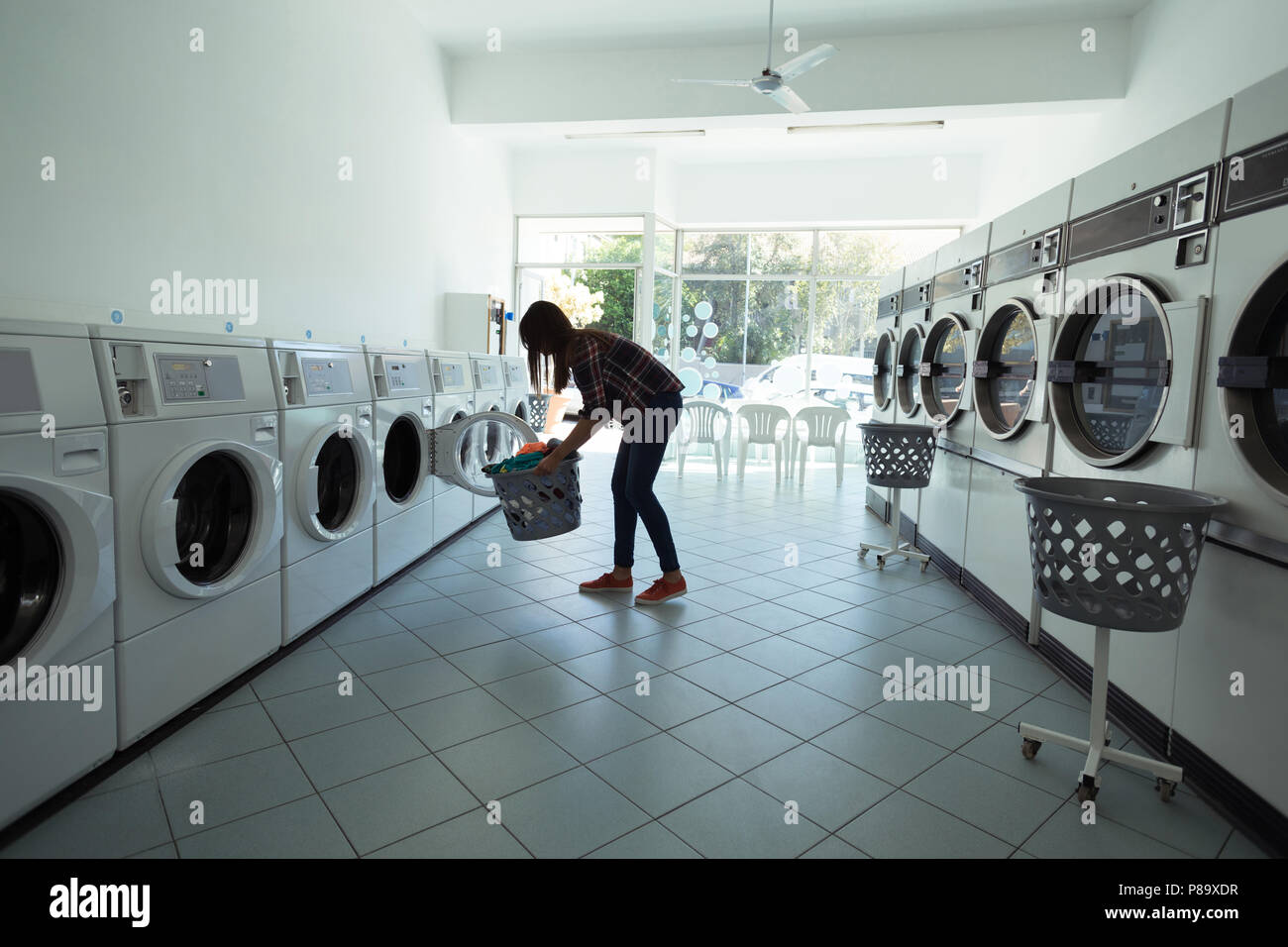 Woman using washing machine at laundromat Stock Photo Alamy