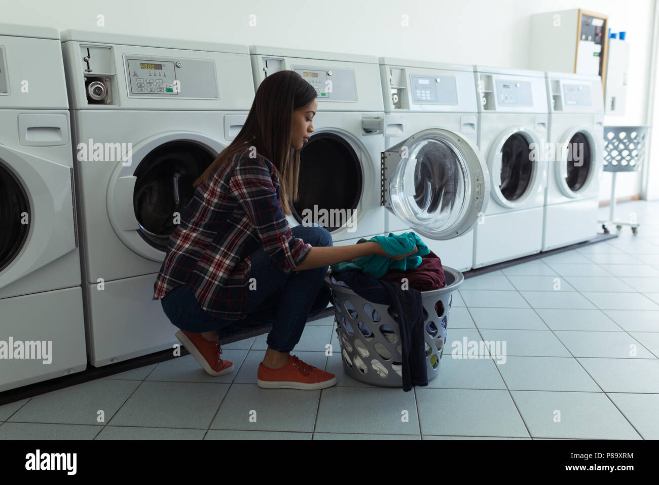 Woman with basket full of clothes in wash house Stock Photo