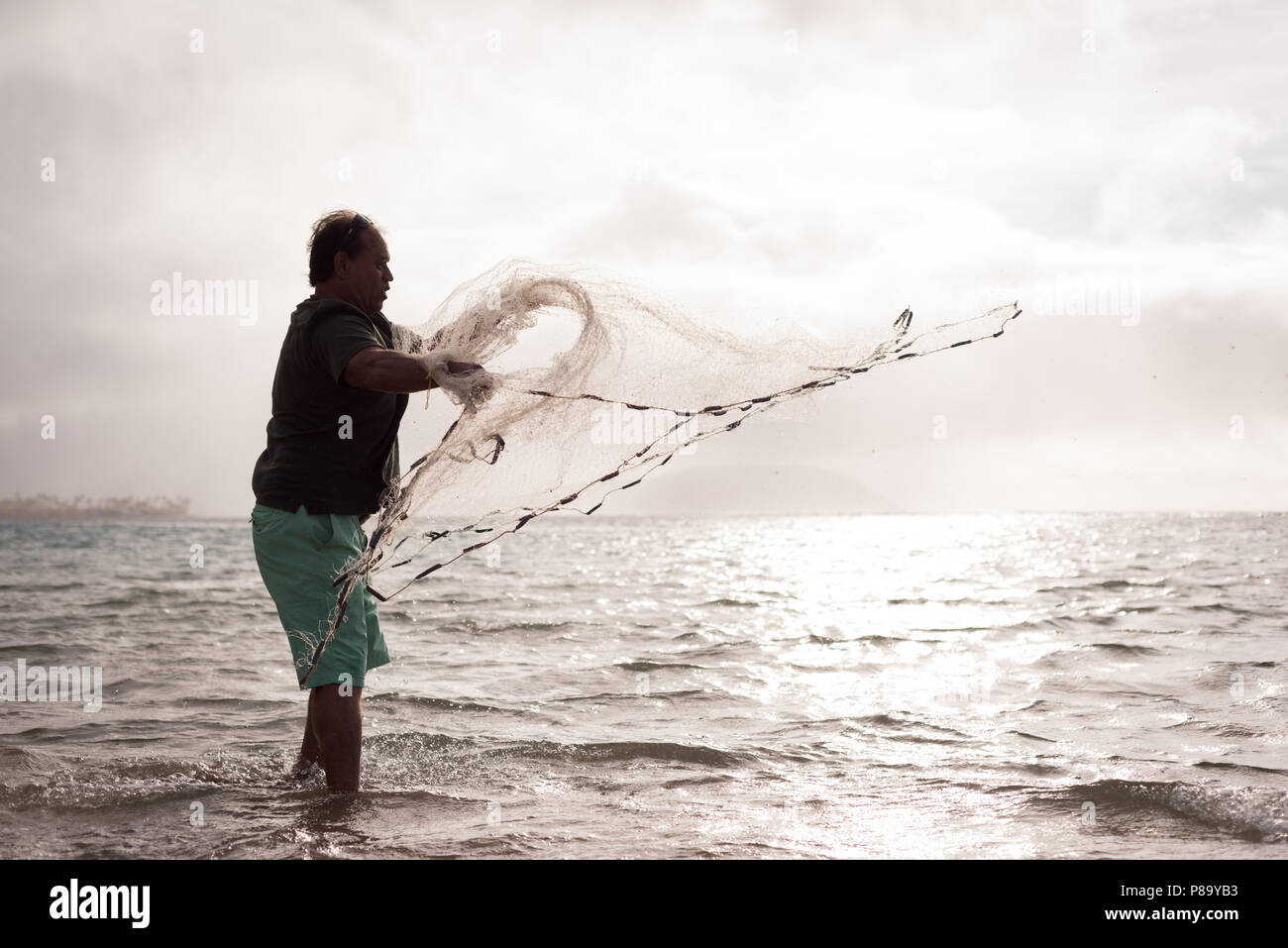 Fisherman throwing fishing net on the beach Stock Photo - Alamy