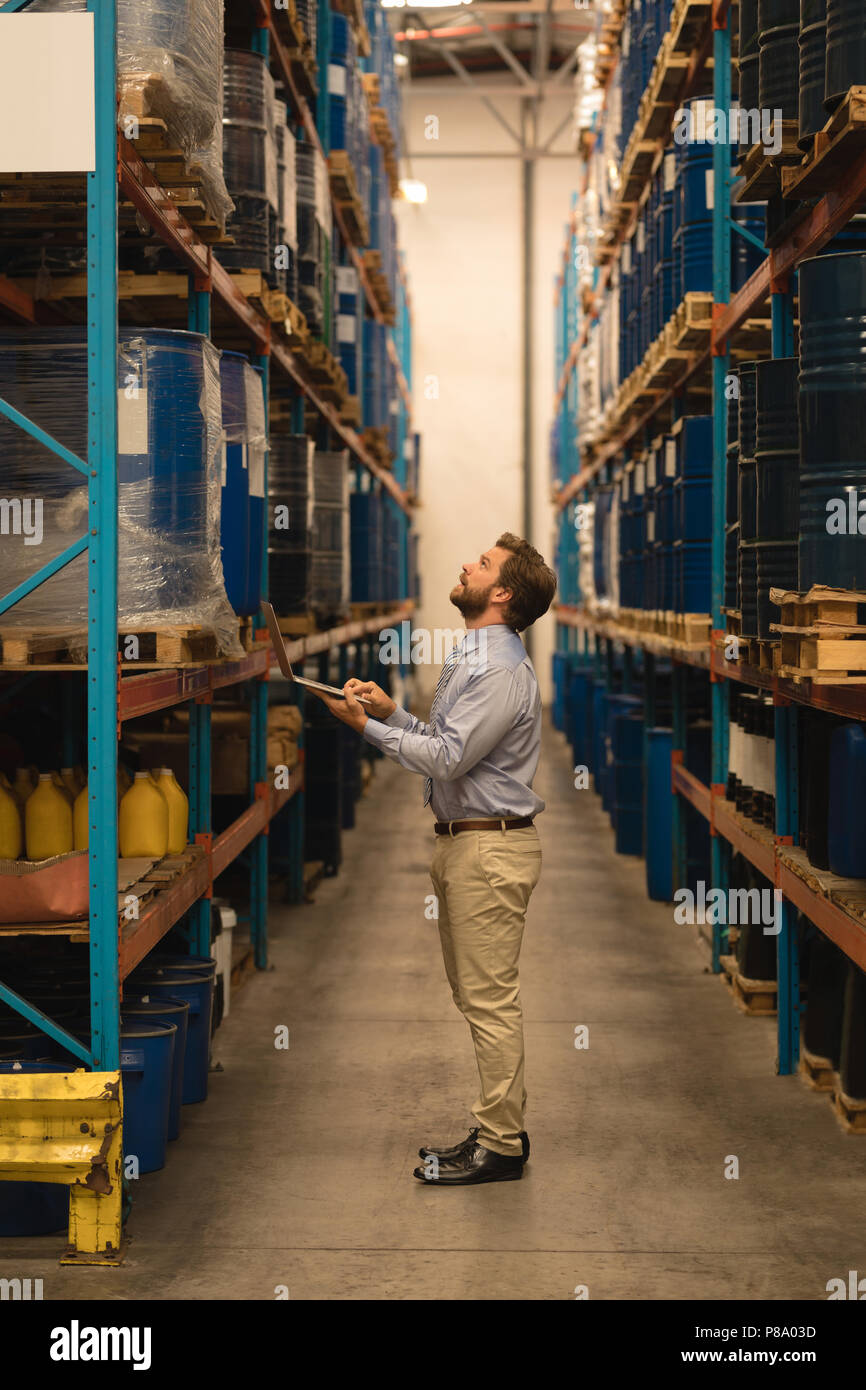 Male manager using laptop while checking stocks Stock Photo
