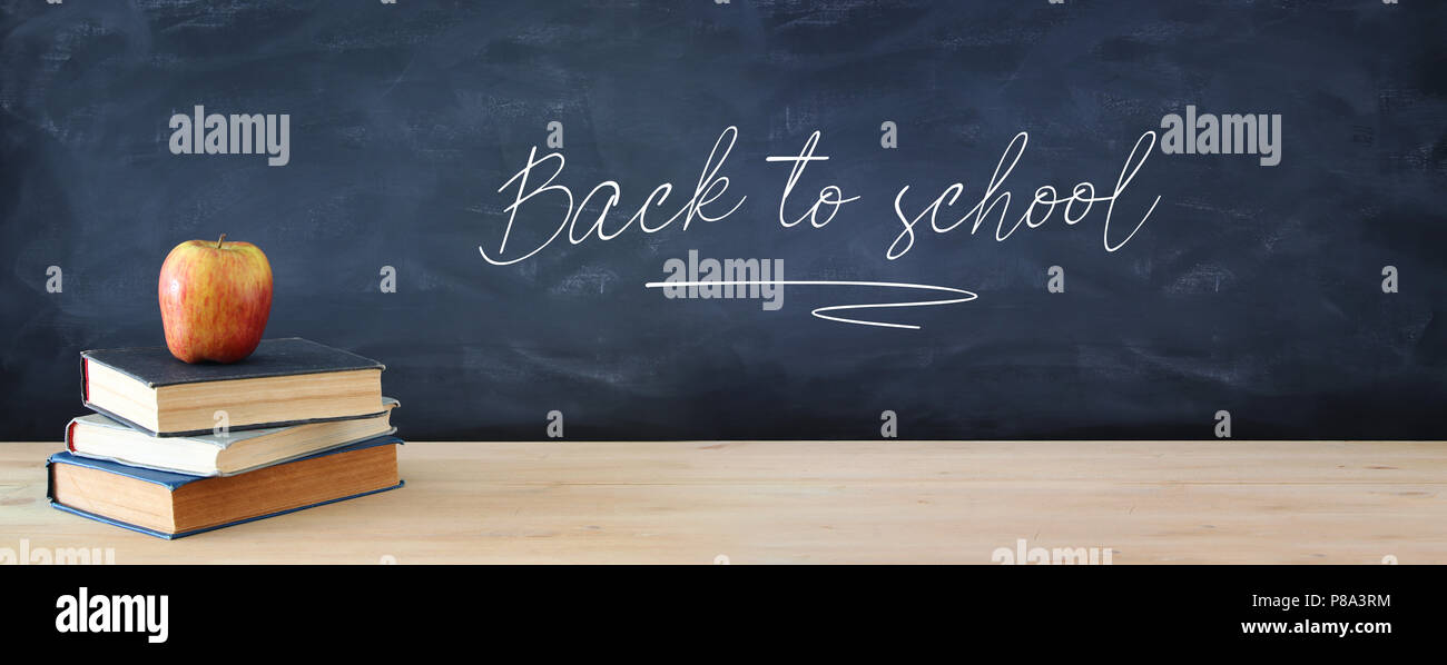 back to school concept. stack of books and apple over wooden desk in ...