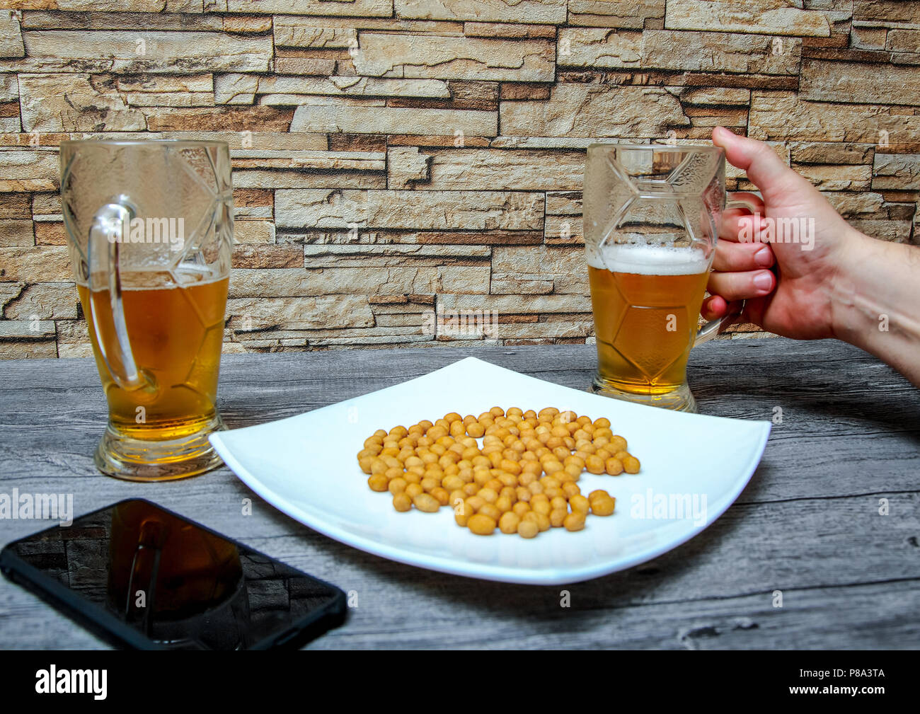 A man's hand holds a half-empty glass of cold beer. Stock Photo