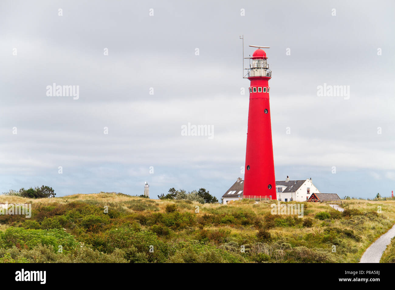 Red lighthouse in the dunes of the Dutch island Schiermonnikoog, next to it the white house of the keeper, in the distance a second lighthouse Stock Photo