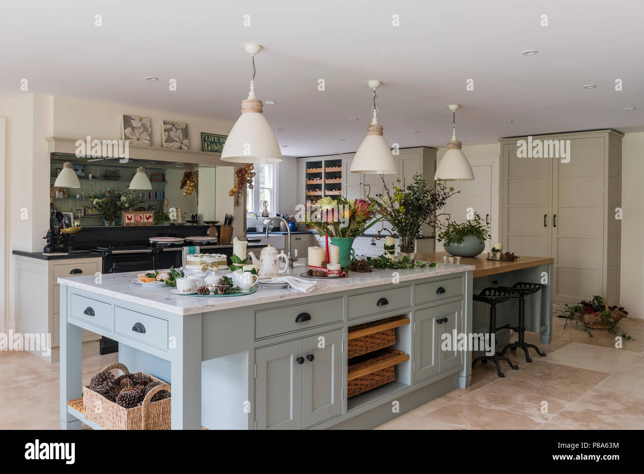 Cream pendant shades above marble topped island unit in Regency farmhouse kitchen Stock Photo