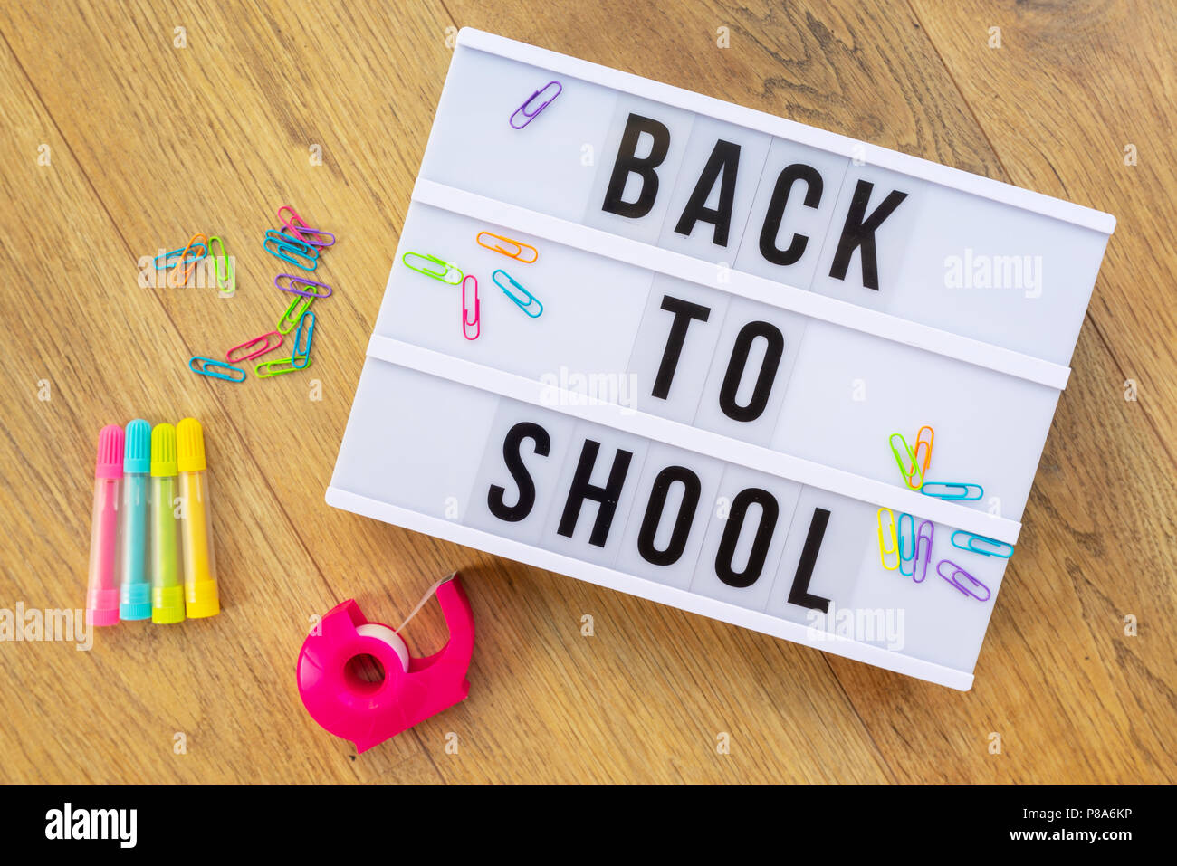 Back to school written on a modern light box on wood background, colorful supplies Stock Photo