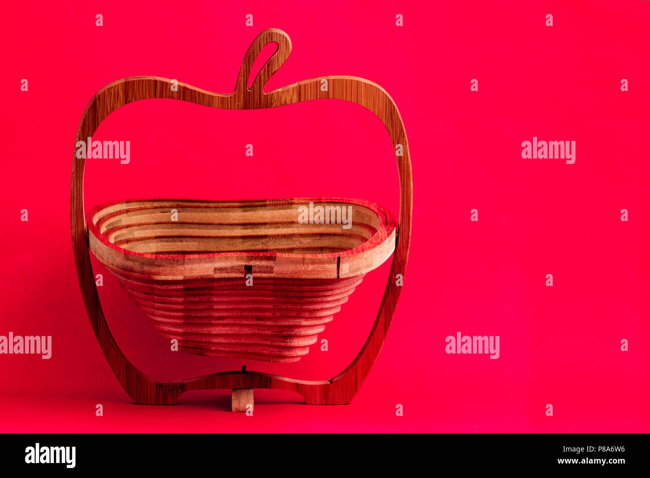 Decorative wooden lazer cut bread or fruit basket on pink background Stock Photo