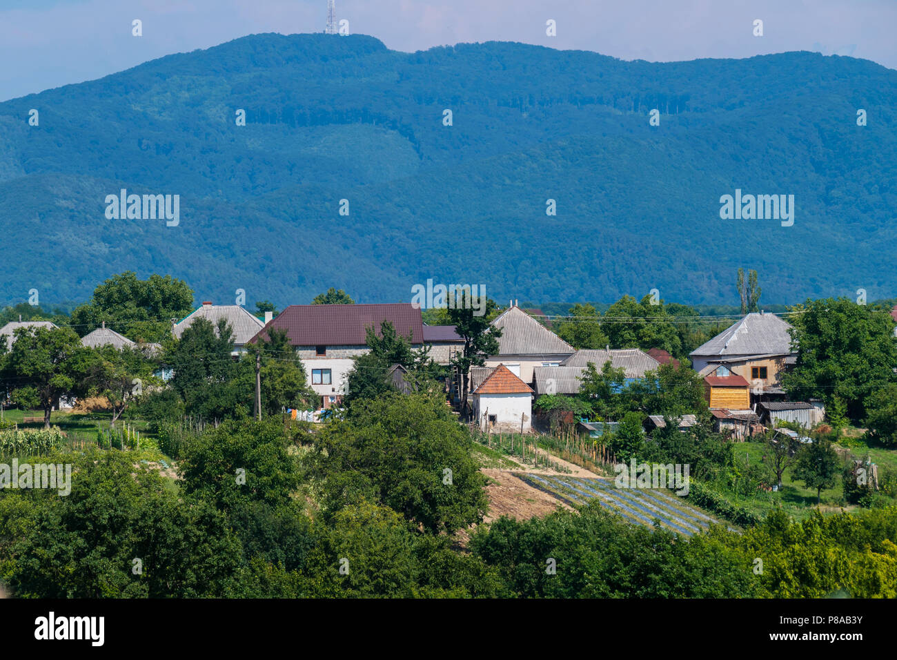 A small rural village is located in a cozy distance from the green rolling mountains . For your design Stock Photo