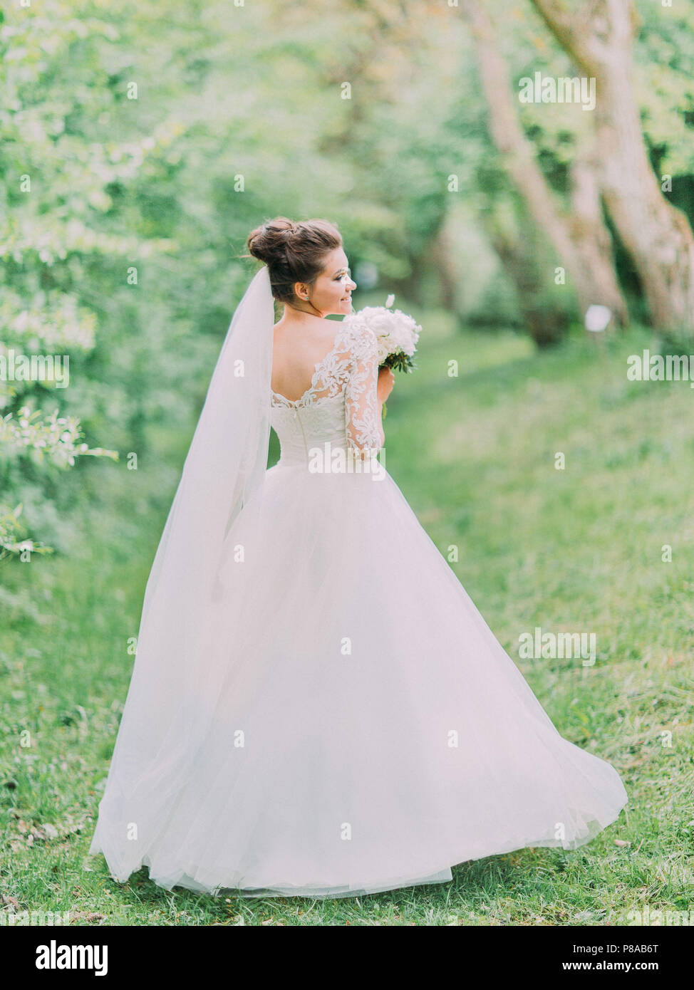 The back view of the charming bride holding the wedding bouquet during ...