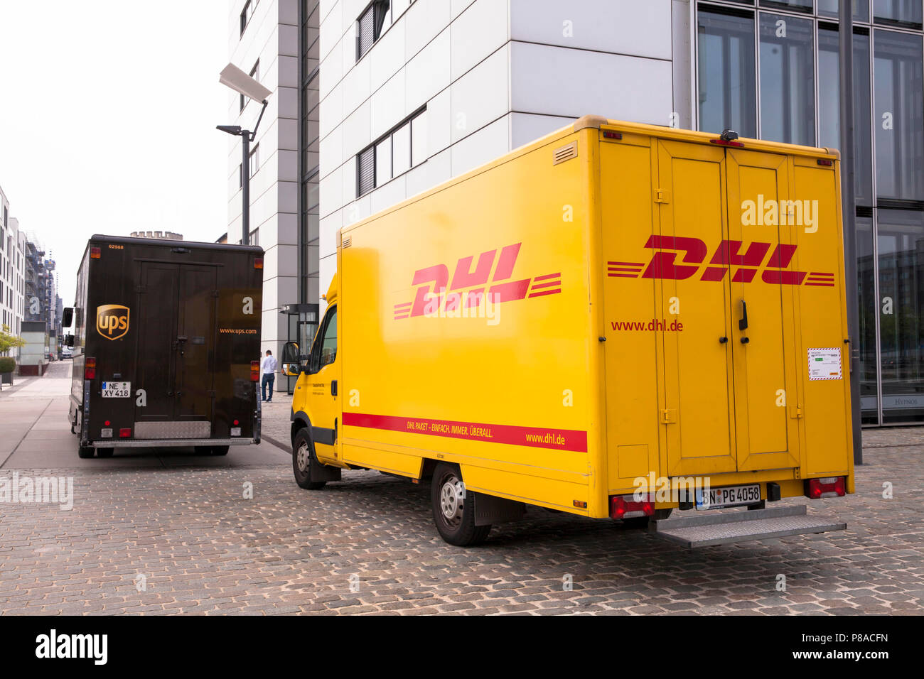 DHL parcel service and UPS parcel service cars in front of Crane House South at Rheinau harbor, Cologne, Germany.  DHL und UPS Fahrzeuge vor dem Kranh Stock Photo