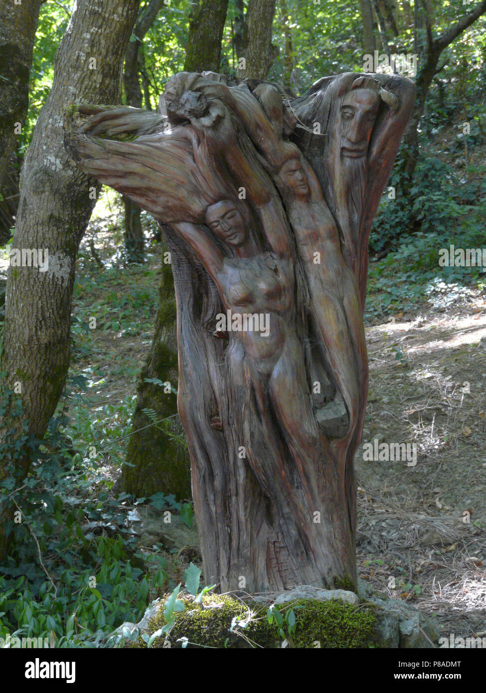 a composition of the figures of girls and a fairy-tale character, carved on the trunk of a tree in the park . For your design Stock Photo