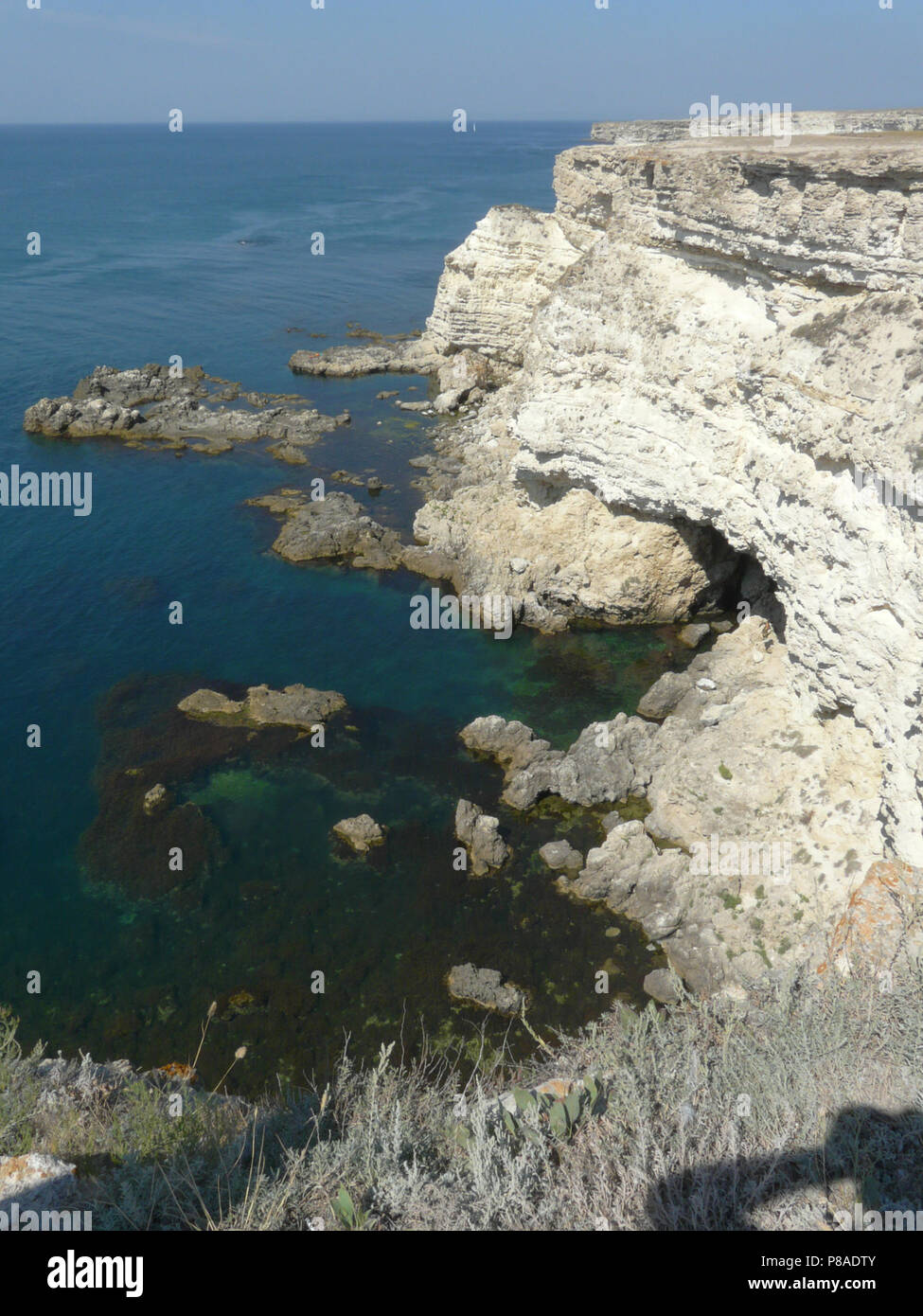 Sea coast with steep rocky slopes and canyons against the backdrop of the endless blue sky . For your design Stock Photo