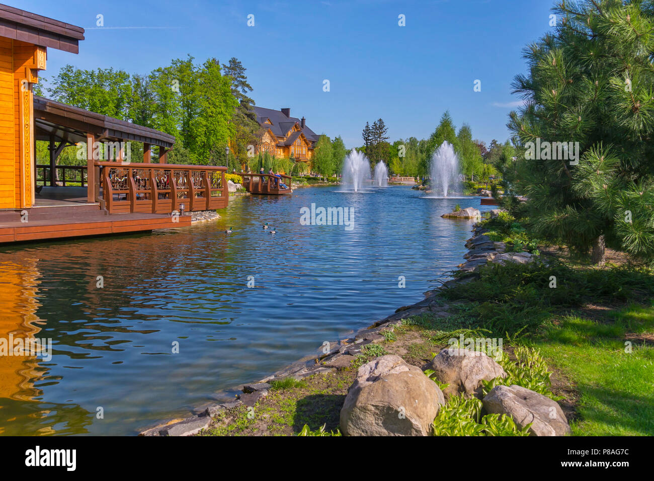 fountains on an artificial lake near wooden houses. A great place to relax in the open air . For your design Stock Photo