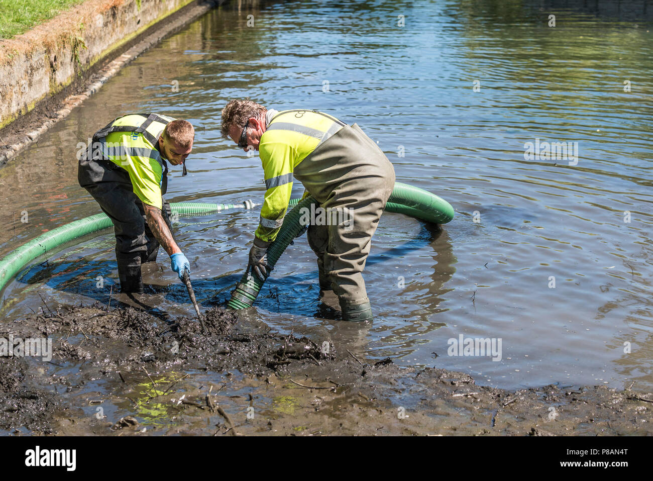 Workers using a suction pump to remove mud and silt in a lake. Stock Photo