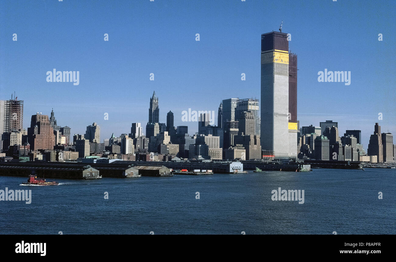 The original World Trade Center’s Twin Towers under construction in 1971 as seen from the Hudson River in New York City, New York, USA. The building of the North Tower (foreground) began in 1968 and the South Tower in 1969. Both structures had been completed and occupied for a decade before they collapsed on September 11, 2001, after being struck by two passenger jetliners hijacked by terrorists. A total of 2,606 people died in the buildings during the disaster. At one time these towering twin structures of the first World Trade Center (WTC) were the tallest buildings in the world. Stock Photo