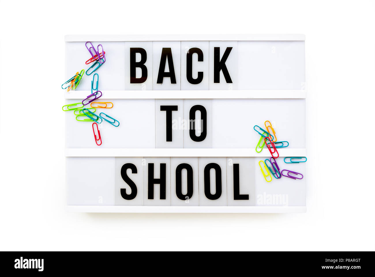 Back to school written on a modern light box on white background, colorful paper clips Stock Photo