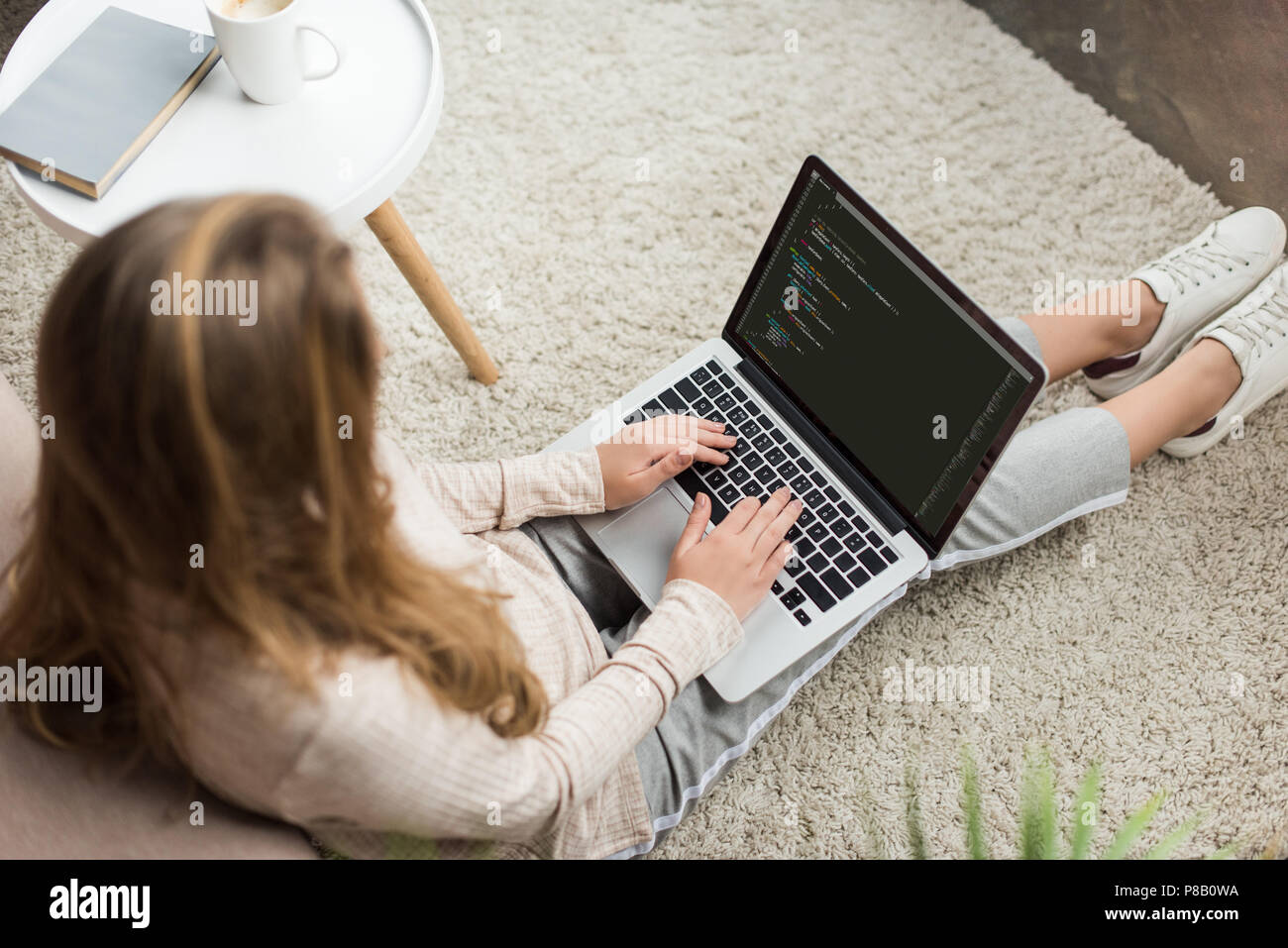 high angle view of young female developer coding with laptop at home Stock Photo