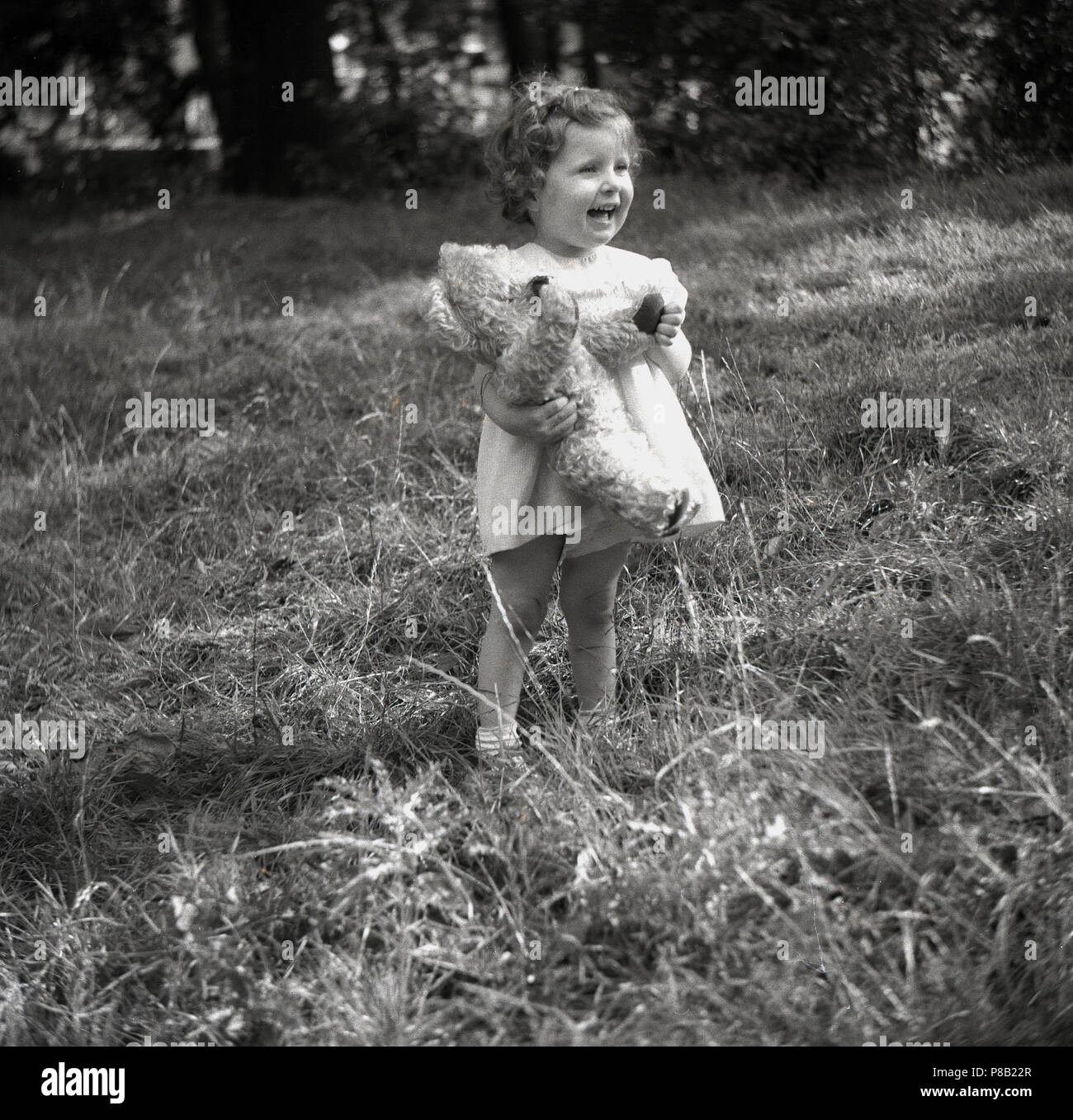 child in field holding her teddy bear Stock Photo - Alamy