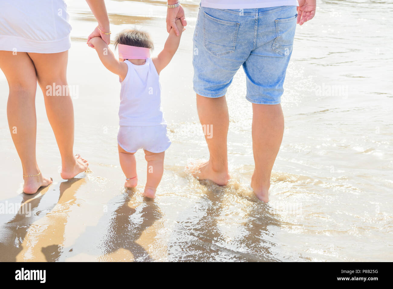 Young Parents Holding By Hands Cute Little Baby Toddler Girl Daughter Learning To Walk Beach Sea Sunlight Authentic Atmosphere Candid Shot With Real Stock Photo Alamy