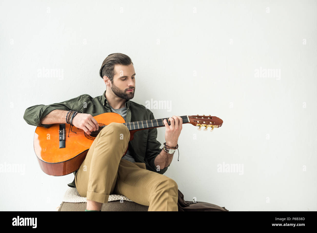 handsome man playing acoustic guitar and leaning on wall isolated on white  Stock Photo - Alamy