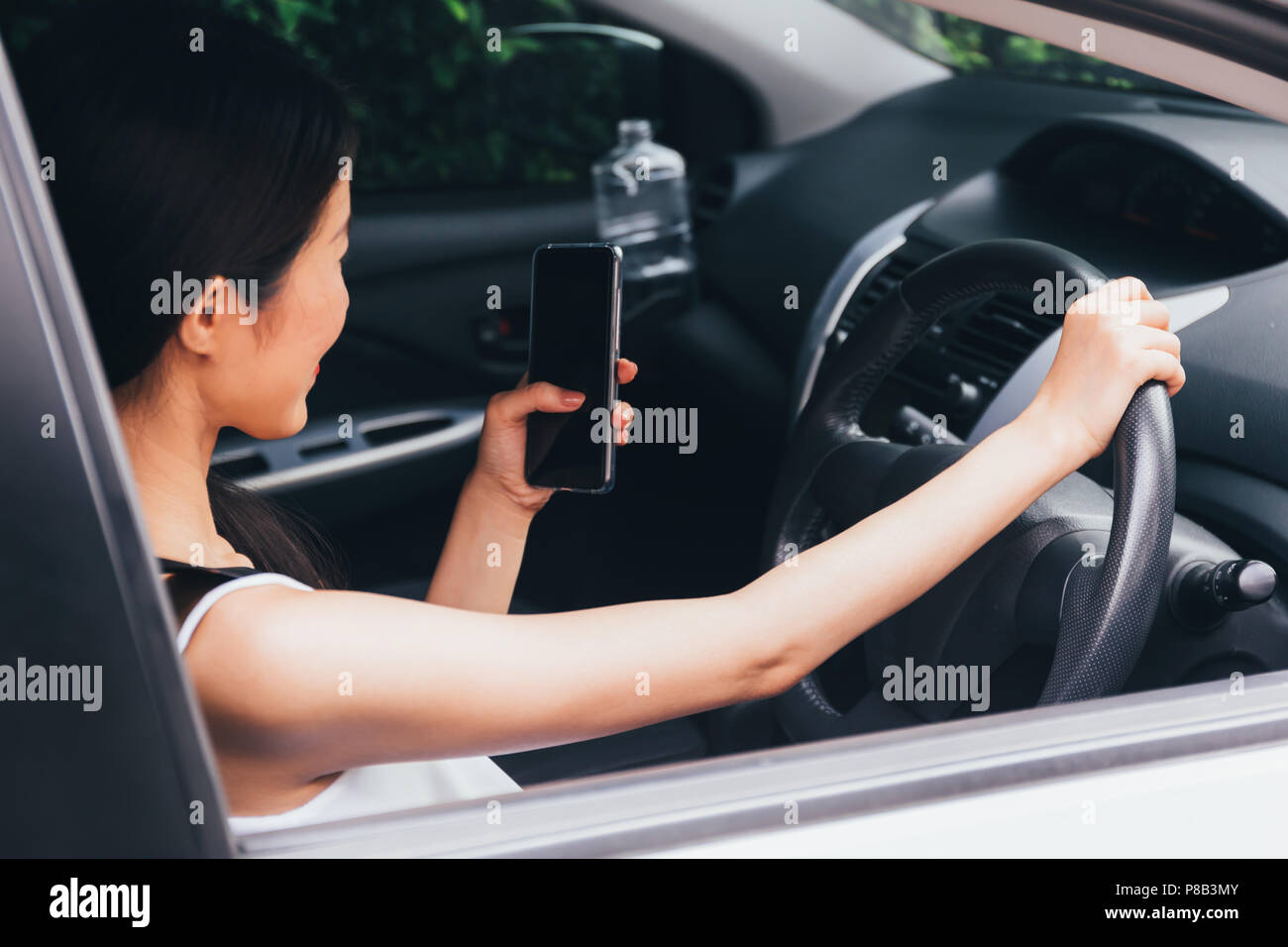 Young Asian woman calling and using a smart phone while driving a car