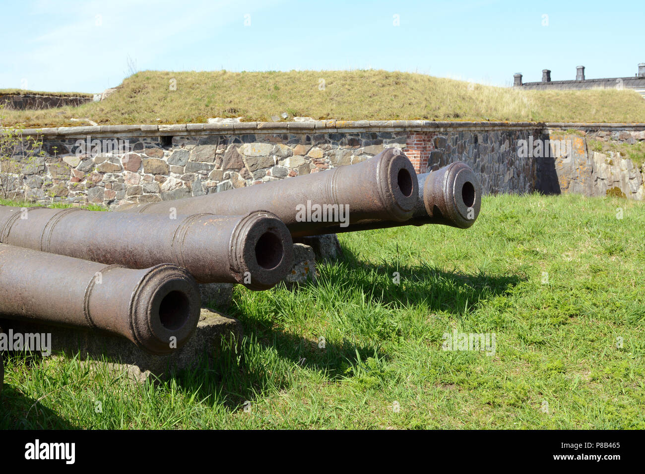 Four old abandoned military cannons on grass in a Suomenlinna bastion Stock Photo