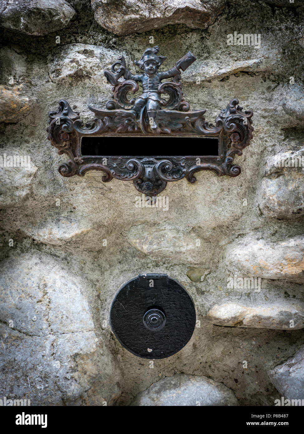 Mailbox with small figurine integrated in a white stonewall, doorbell