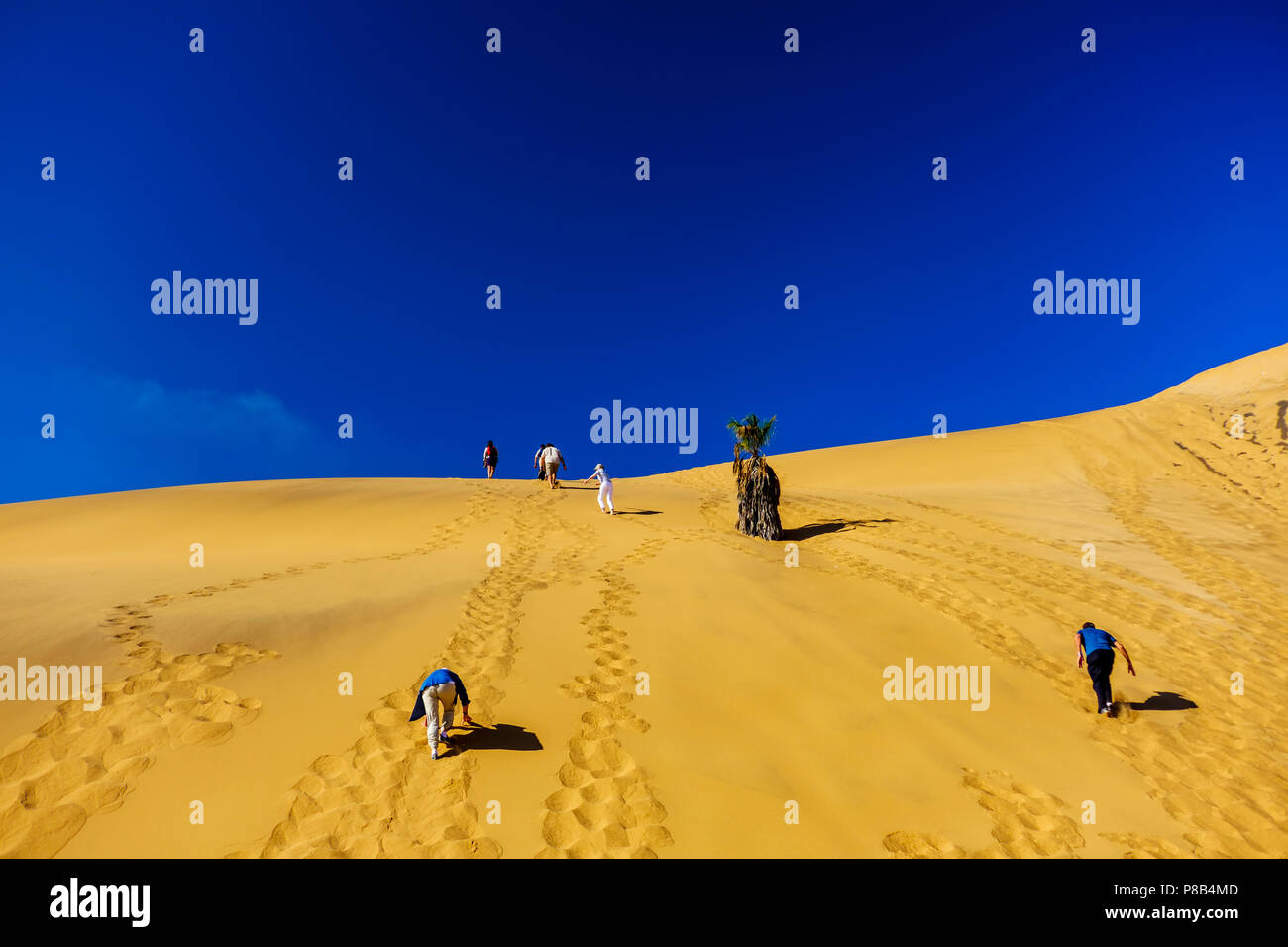 Against background of clear deep blue sky tourists climb the beautiful