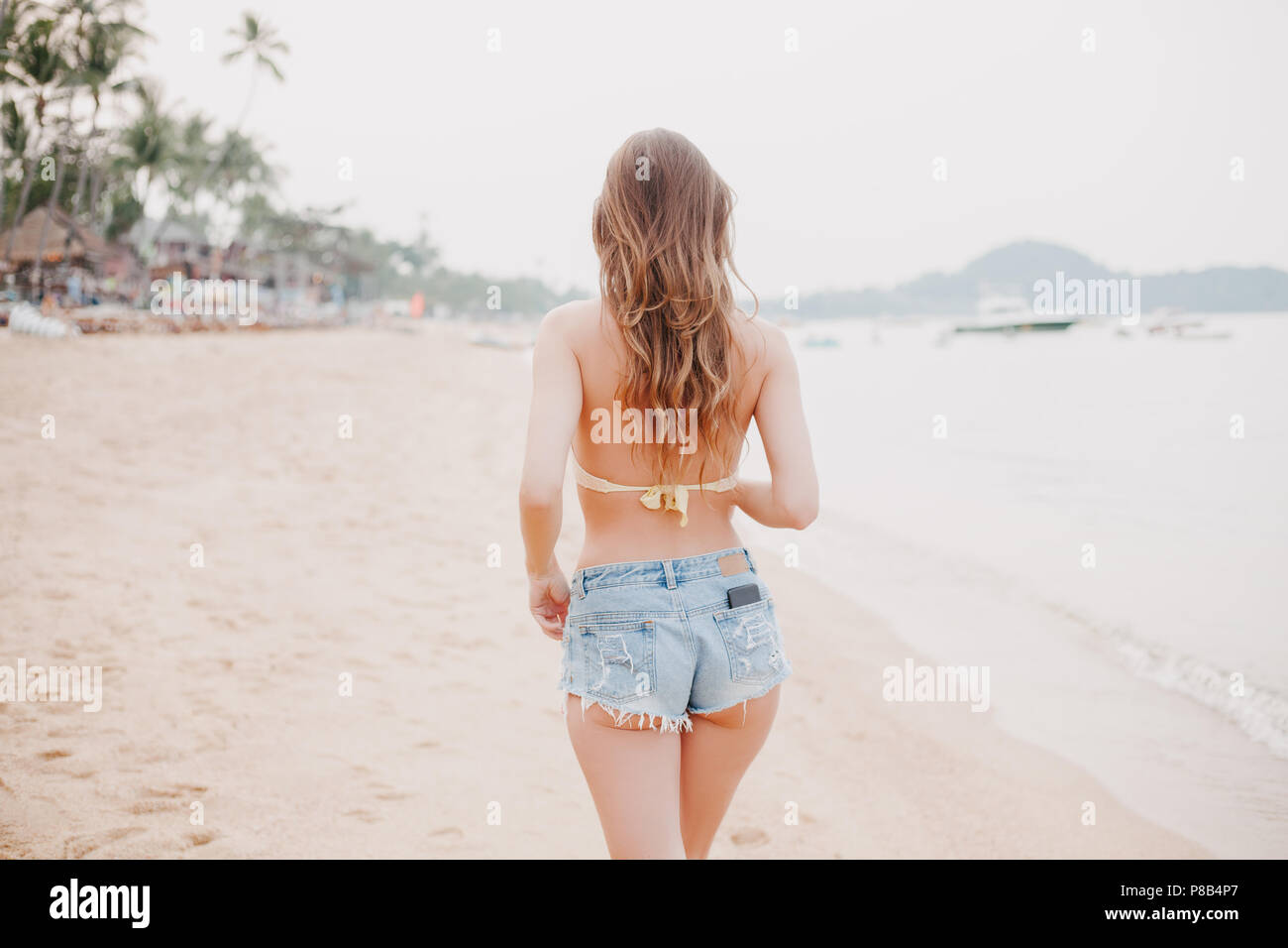 woman walking on sandy beach in shorts 