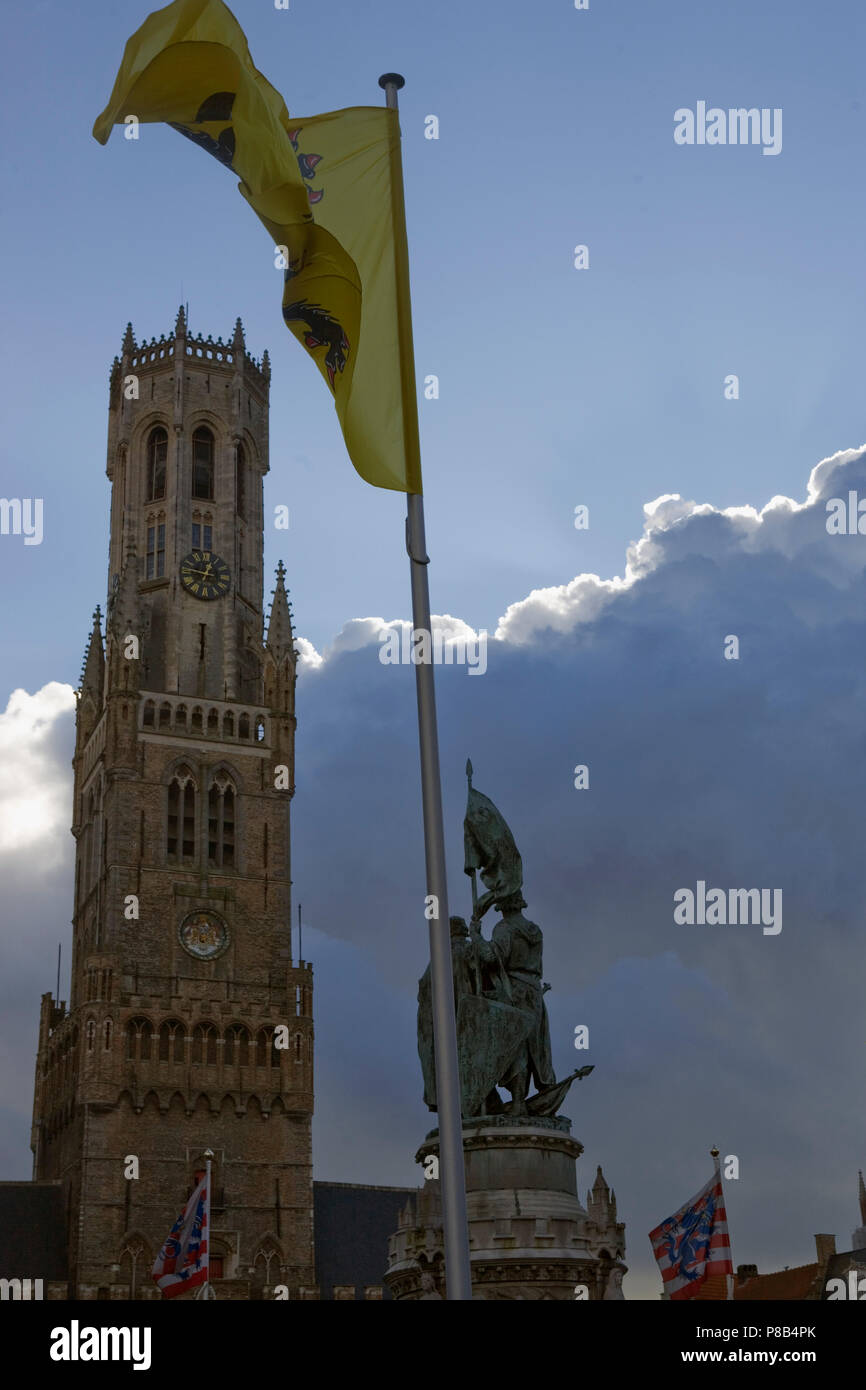 The soaring gothic Belfort, or Belfry Tower of the Hallen in the Markt, Brugge, Belgium, with flags and statue Stock Photo